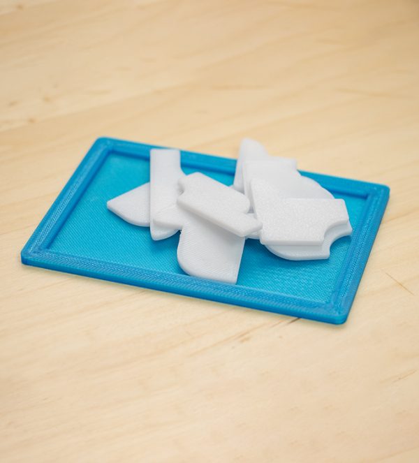 Puzzle 3D cu 10 piese albe, așezate pe o ramă albastră, realizat prin printare 3D, nivel dificultate 8/10.